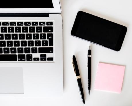 a silver Mac, an iphone, 2 pens