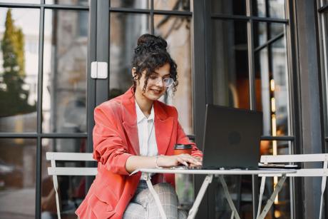 ndian woman working on a laptop in a street cafe.