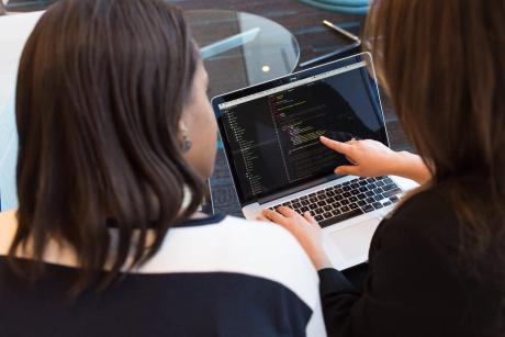 Two women discussing pointing at a laptop