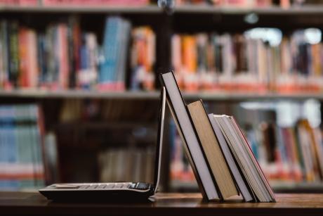 laptop computer and book on workplace in library room