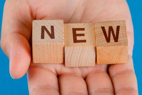 hand holding wooden cubes with word new.