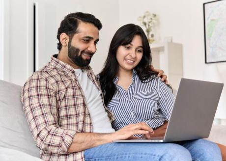 husband and wife on couch going through laptop