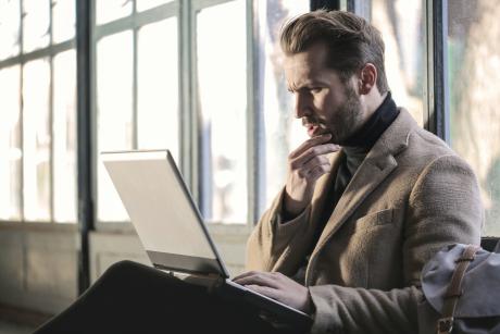 Man confusedly staring at his laptop screen