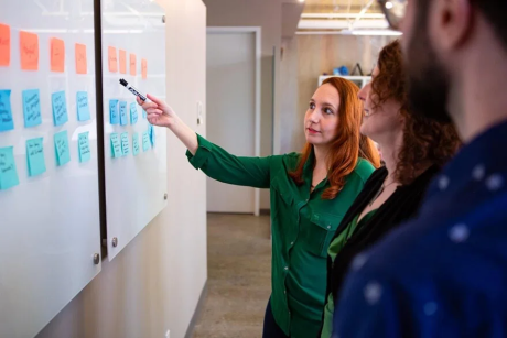 person pointing at sticky notes at board