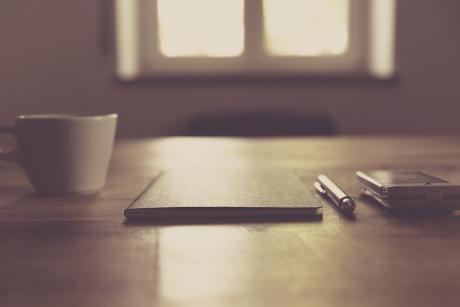 A coffee cup, diary, pen and mobile phone on a table