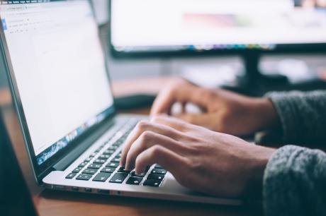 A pair of hands typing on a laptop