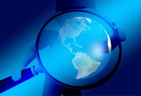 A giant magnifying lens held in the hands of a human figure, with the image of earth in the middle