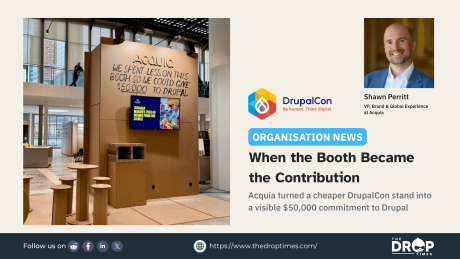 Acquia's cardboard exhibition booth at DrupalCon Rotterdam with a handwritten message stating that the company spent less on the booth so it could give $50,000 to Drupal.