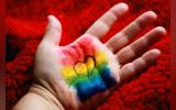 Photo captured by Alexander Grey taken from unsplash.com. The picture shows a hand with diversity flag colours painted on the palm and a heart in black ink over it.