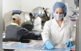 Three people inside a factory wearing masks and coats