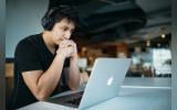 A man listening to something while looking at his laptop