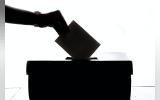 a person is casting a vote into a box