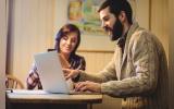Couple interacting while using laptop and mobile phone