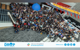 Group photo from DrupalCon Portland 2024 where attendees gather in the corridor and a giant Drupal Icon ballon is seen in the backdrop