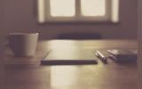 A coffee cup, diary, pen and mobile phone on a table