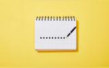 a pen marking dots on a notepad