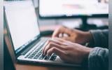 A pair of hands typing on a laptop