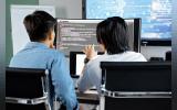 Two developers working together in an office, discussing code on a screen